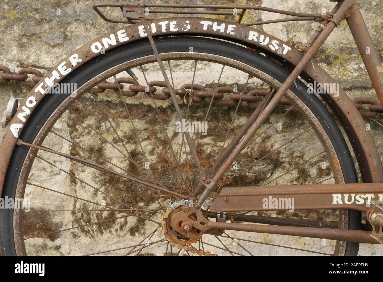 Un vieux vélo rouillé enchaînés à un mur à Paris.La rouille dans la paix en écrit sur le côté. Banque D'Images