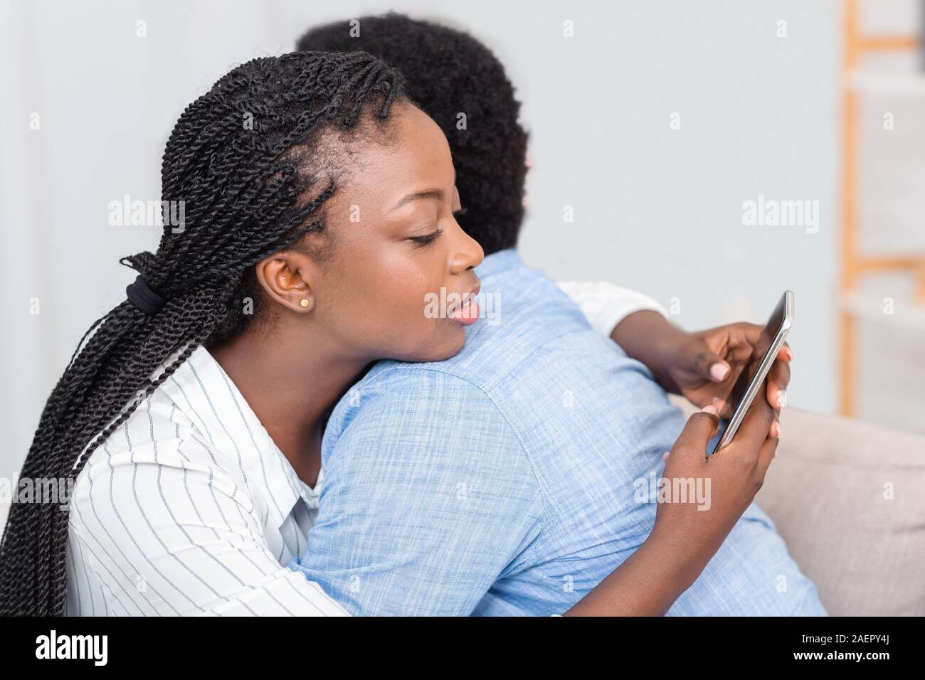 Tricher femme texting on cellphone avec quelqu'un tout en embrassant son mari Banque D'Images