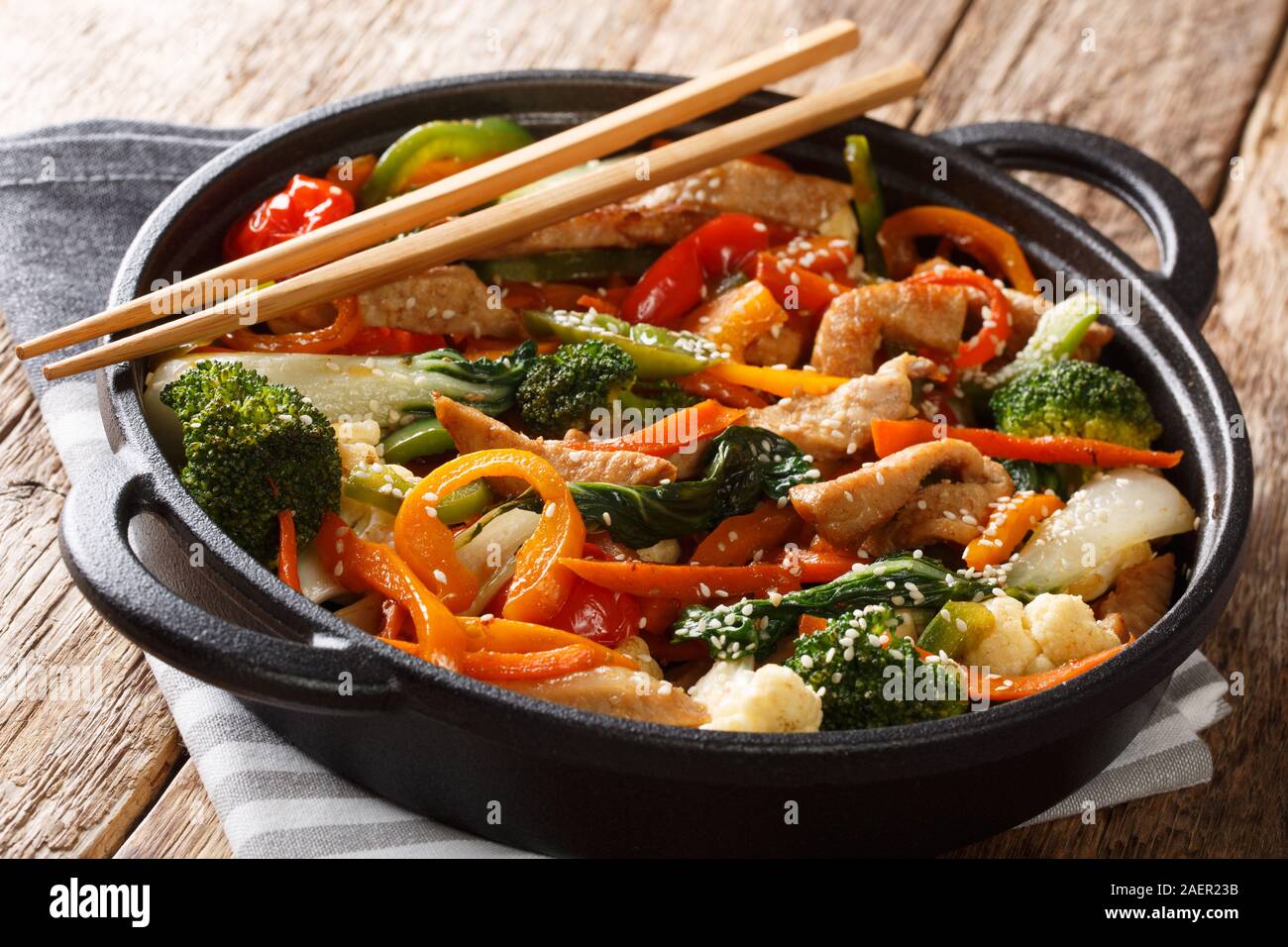 Porc frit style asiatique avec brocoli, bok choy, carottes, poivrons, chou-fleur close-up dans une casserole sur la table horizontale. Banque D'Images
