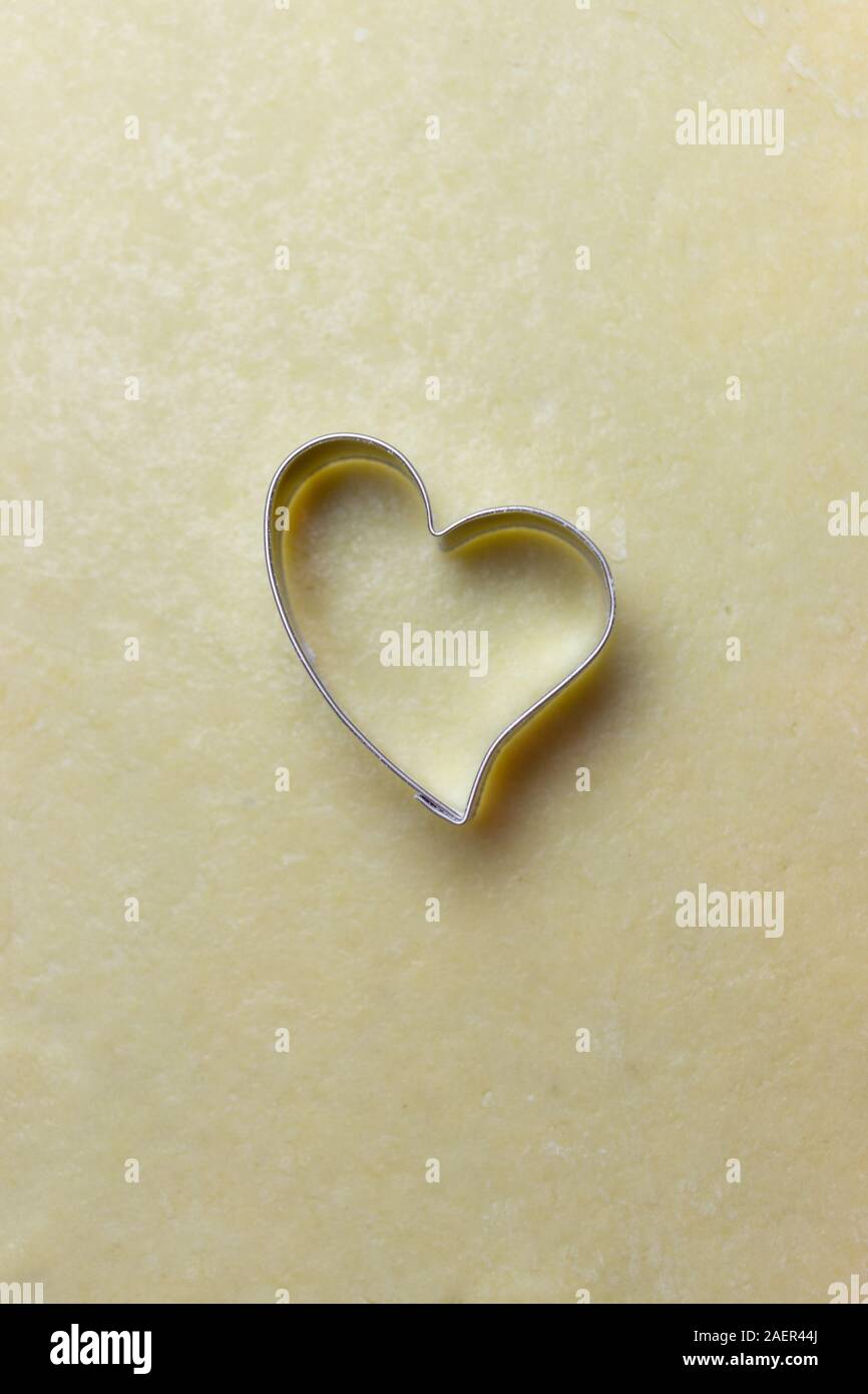 Fermer la pâte à biscuits de Noël en forme de coeur avec la faucheuse. Vue de dessus la pâte de fond avec copie espace pour le texte. Concept de boulangerie de Noël Banque D'Images