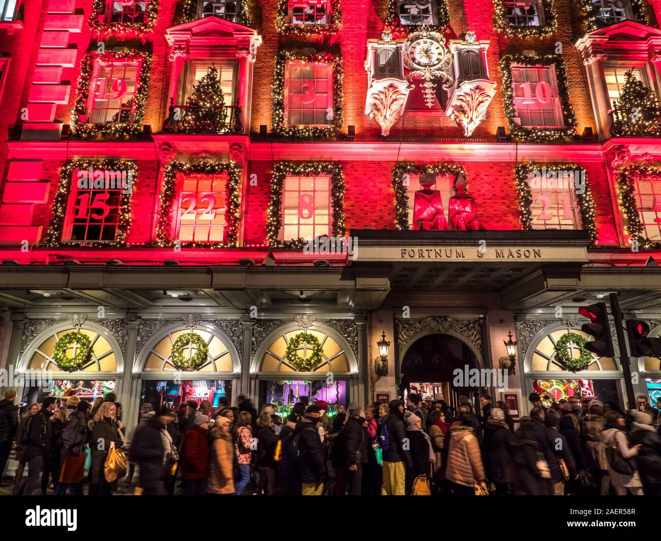 Fortnum & Mason Noël department store façade, avec un calendrier de l'avent rouge nuit à thème très occupé avec des files d'attente et de la foule des acheteurs de Noël Piccadilly Londres UK 2019 Banque D'Images