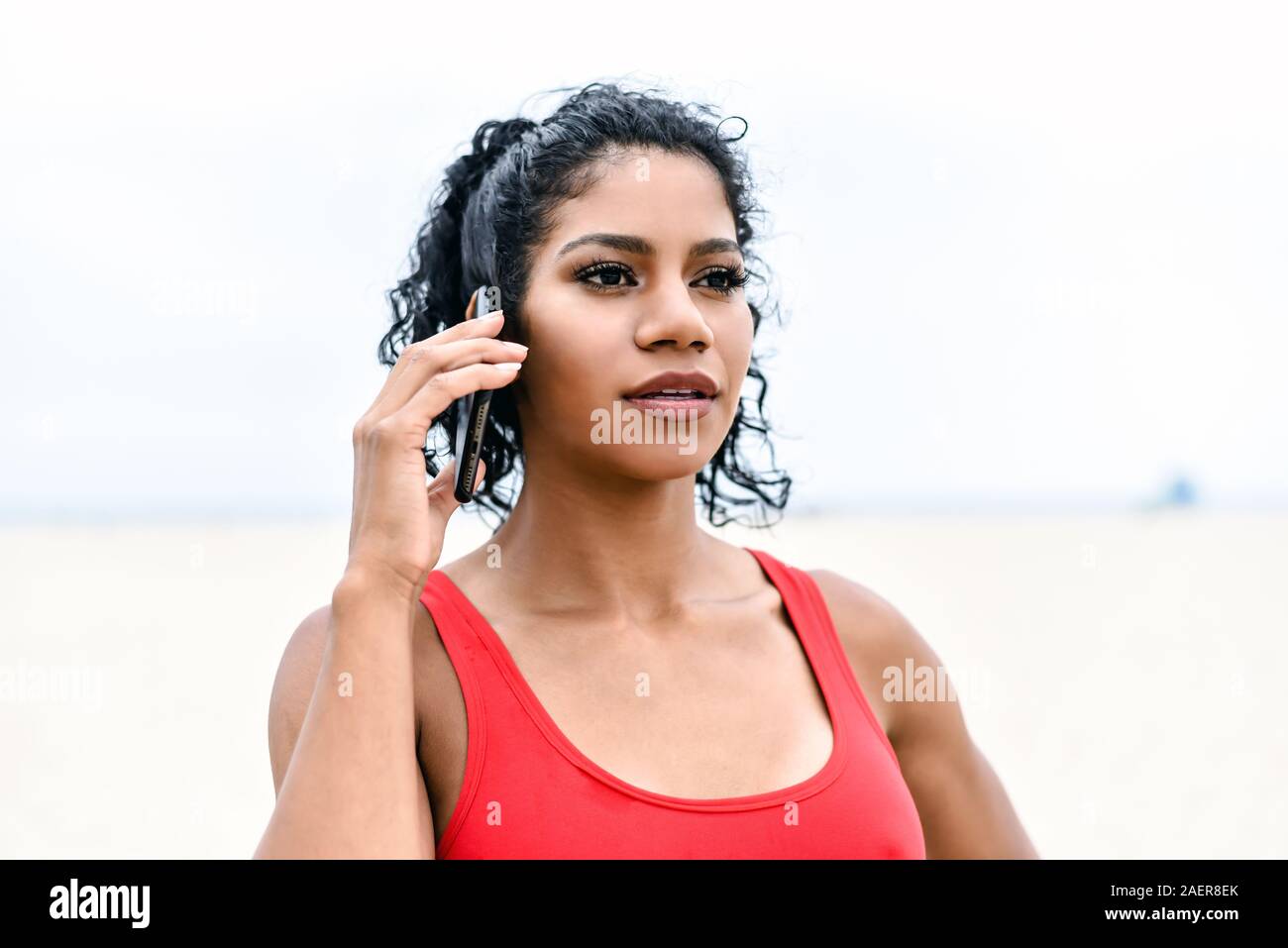 Jeune femme est titulaire d'un téléphone portable à l'oreille de l'écoute d'un appel téléphonique. Banque D'Images