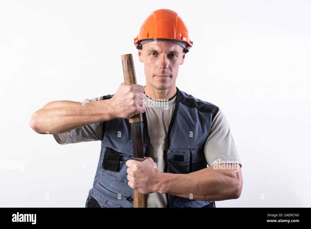 Un constructeur avec une grande épée sur son épaule. Réparateur portant un casque et des vêtements de travail. Banque D'Images