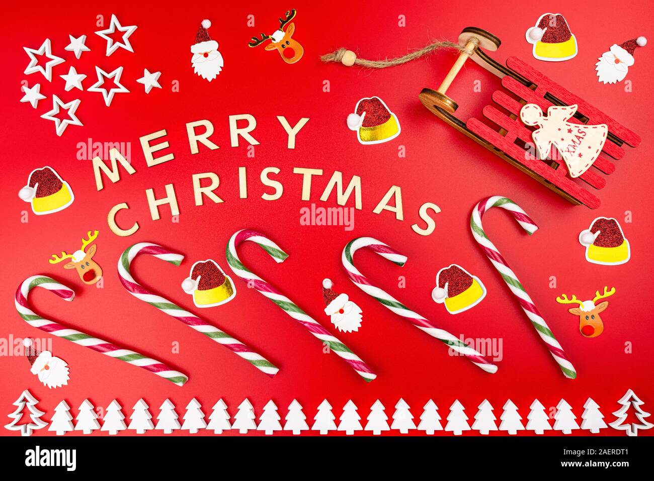 L'inscription Joyeux Noël faits de lettres, posé à plat à partir de  ci-dessus, isolé sur un fond rouge. Des cannes de bonbon visibles, tre Noël  en bois Photo Stock - Alamy