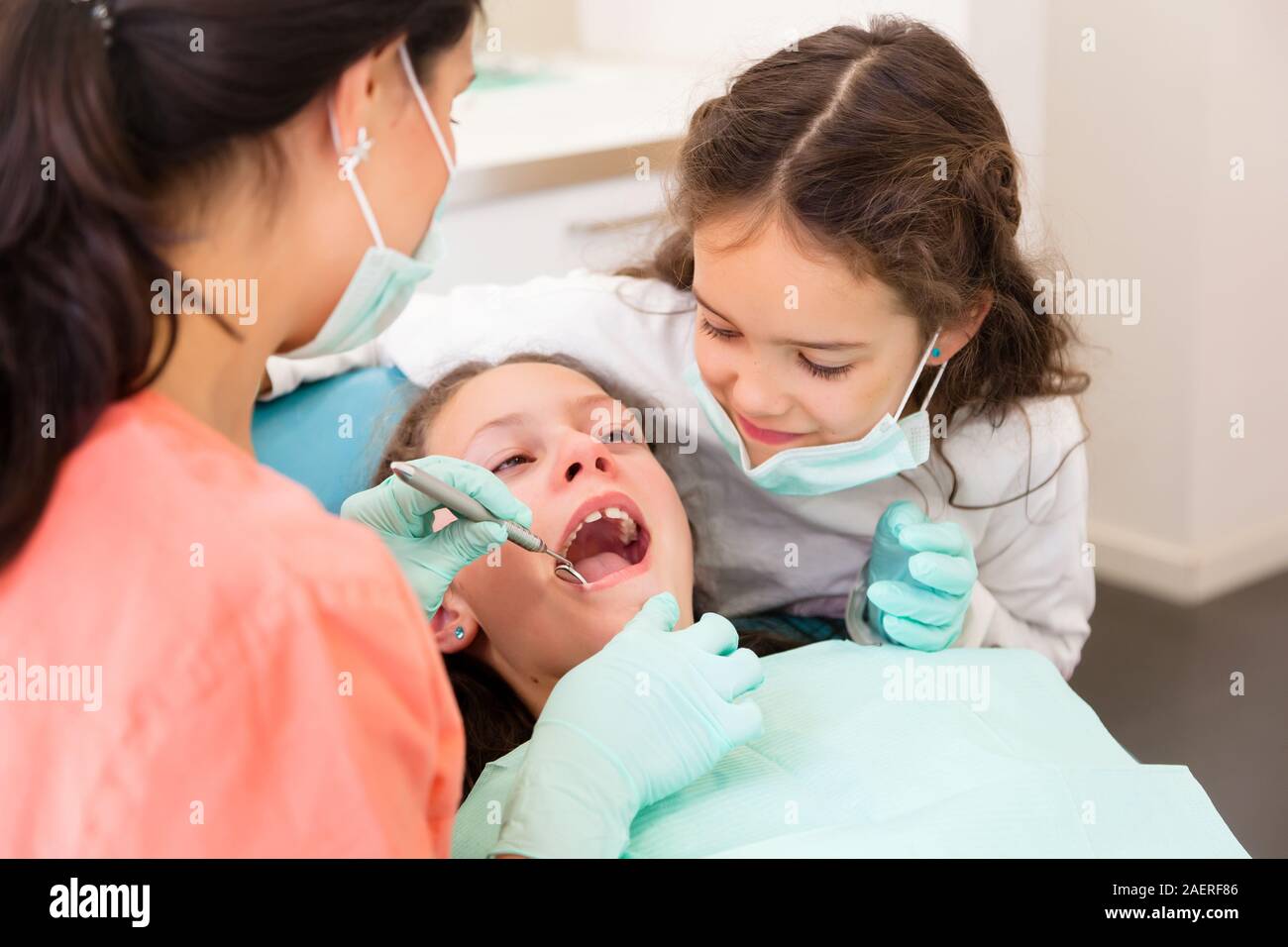 Adorables enfants dentiste en chirurgie dentaire avec deux jolies jeunes filles en leur montrant examen dentaire, une fille est à l'assistant Banque D'Images