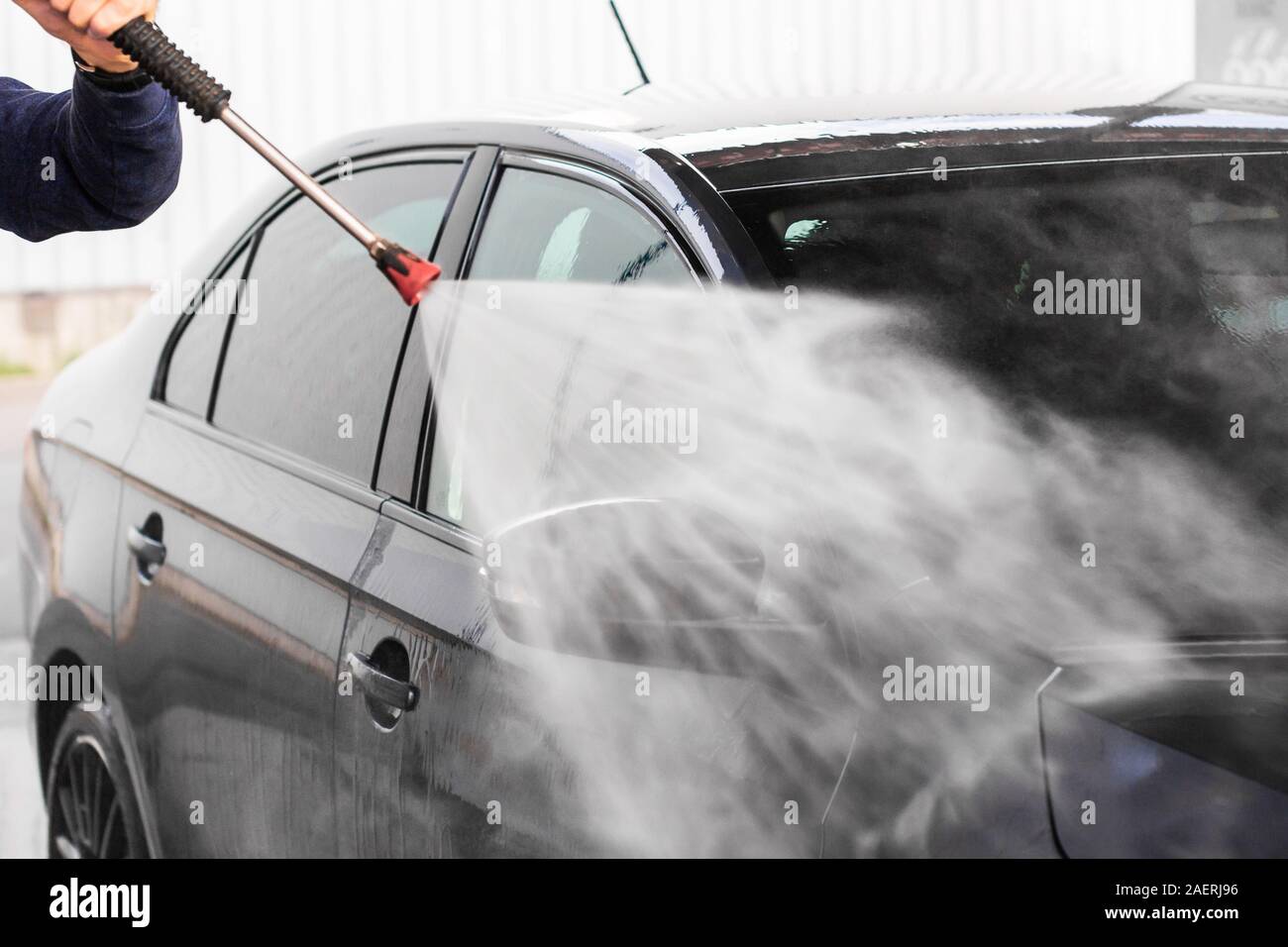 Un homme se lave une voiture à self service de lavage de voiture. Véhicule haute pression machine lave-glace avec de l'eau propre. Équipement de lavage de voiture Banque D'Images