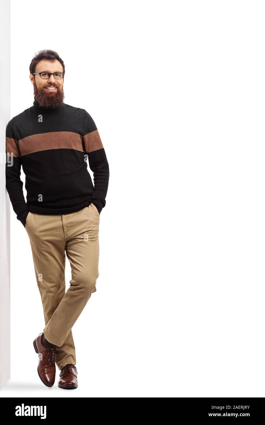 Portrait d'un homme barbu dans un cardigan à col roulé s'appuyant sur un mur isolé sur fond blanc Banque D'Images