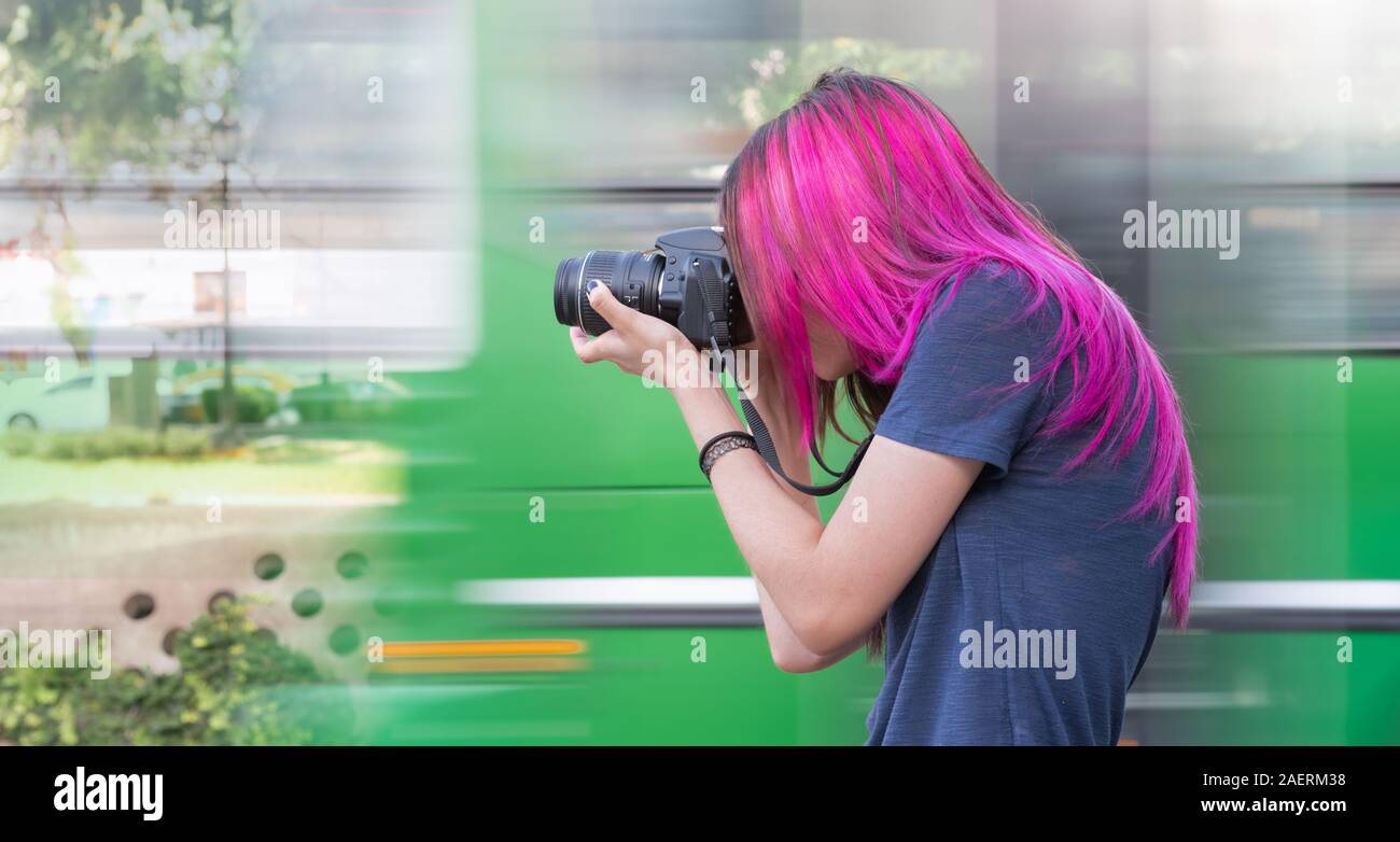 Une fille de prendre des photos avec un appareil photo DSLR avec arrière-plan déplacé Banque D'Images