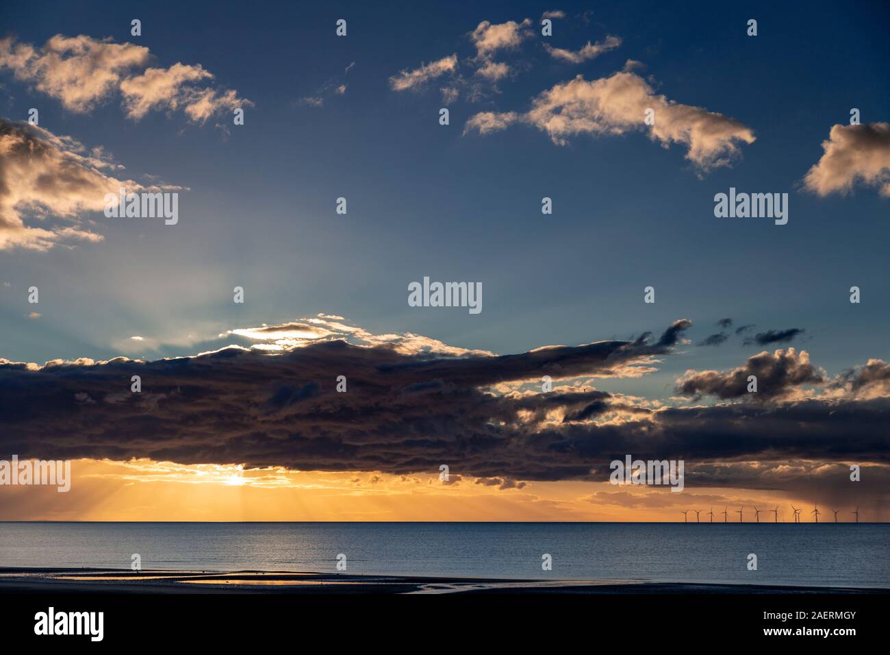 Coucher du soleil sur la mer d'Irlande de Muro, au nord du Pays de Galles, avec des rayons de soleil et nuages Banque D'Images