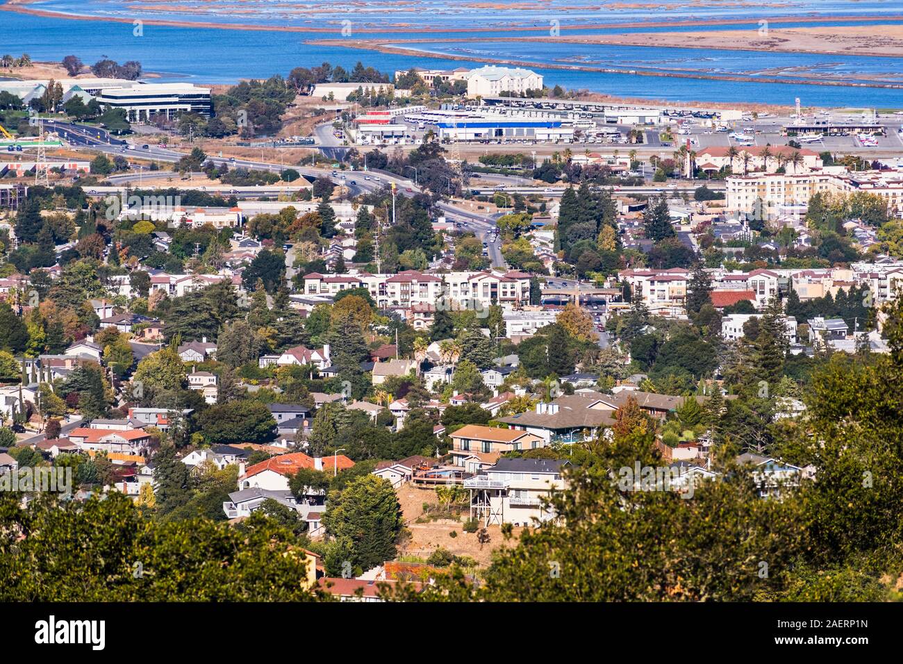 Vue aérienne de San Carlos, dans la Silicon Valley ; des zones résidentielles avec des maisons construites sur des collines en premier plan ; les zones industrielles et le rivage de sa Banque D'Images
