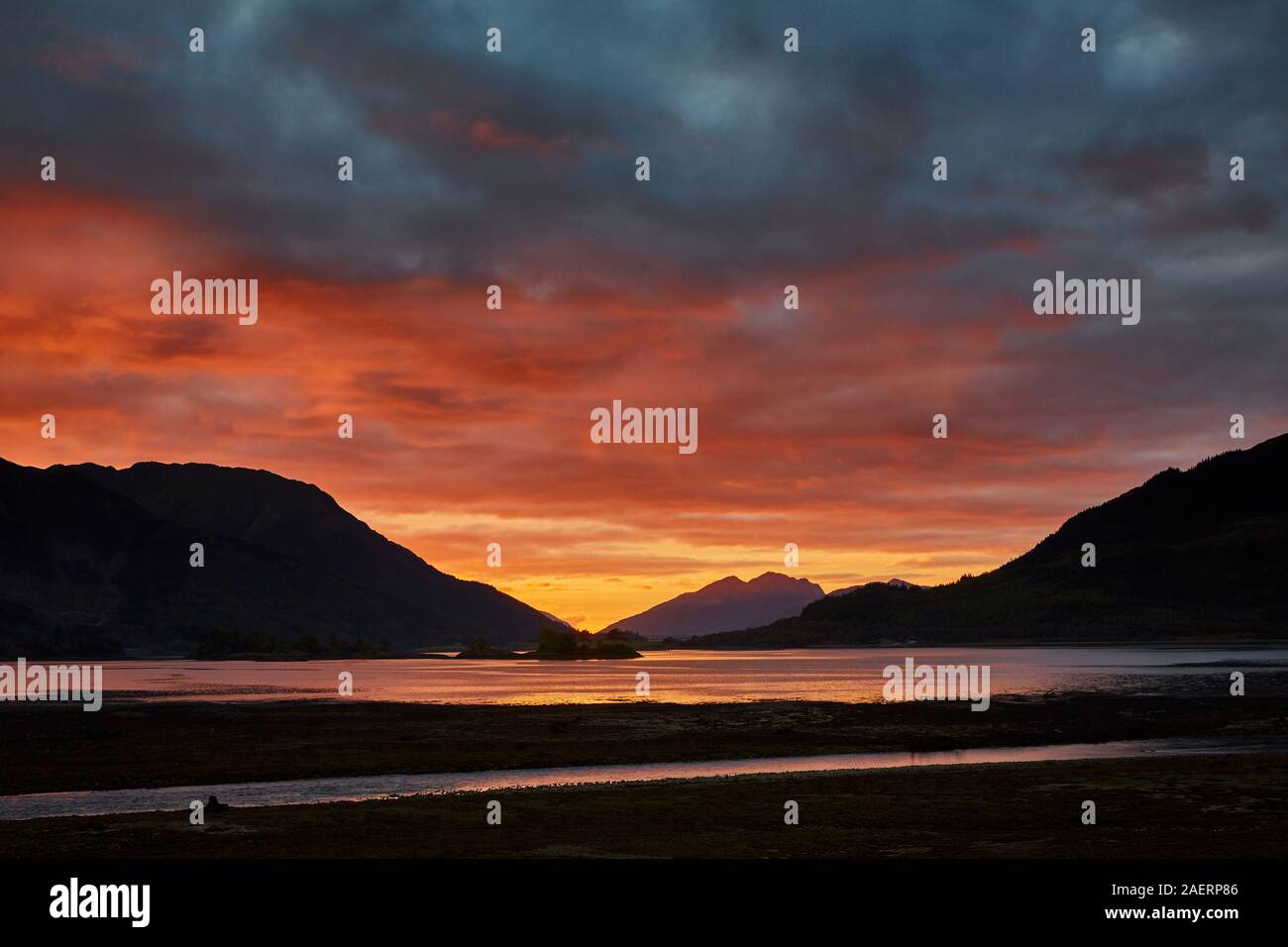 Un spectaculaire coucher de soleil sur le Loch Leven au cours d'une soirée d'automne avec les couleurs des nuages se reflétant dans l'eau et les montagnes en silhouette Banque D'Images