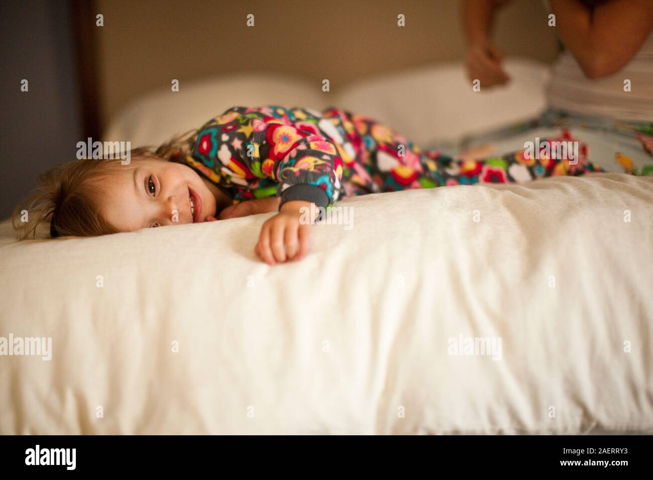 Smiling girl lying on bed en pyjama. Banque D'Images