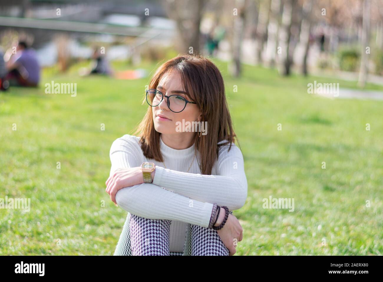 Jeune fille, assise dans l'herbe d'un parc, à la recherche de son droit Banque D'Images