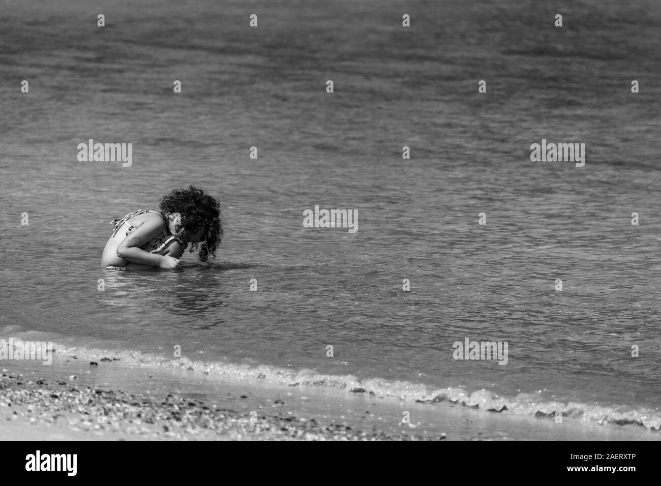 Afrique Litlle girl brésilienne jouer seul à la plage. Noir et blanc. Banque D'Images