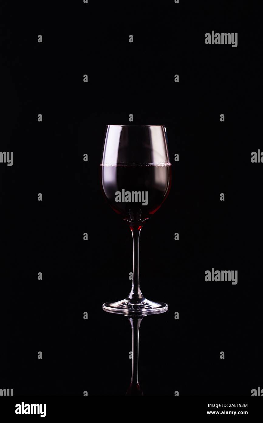 Verre de vin rouge sur fond noir. Vin aromatique. Style strict. Vin sur le noir Banque D'Images