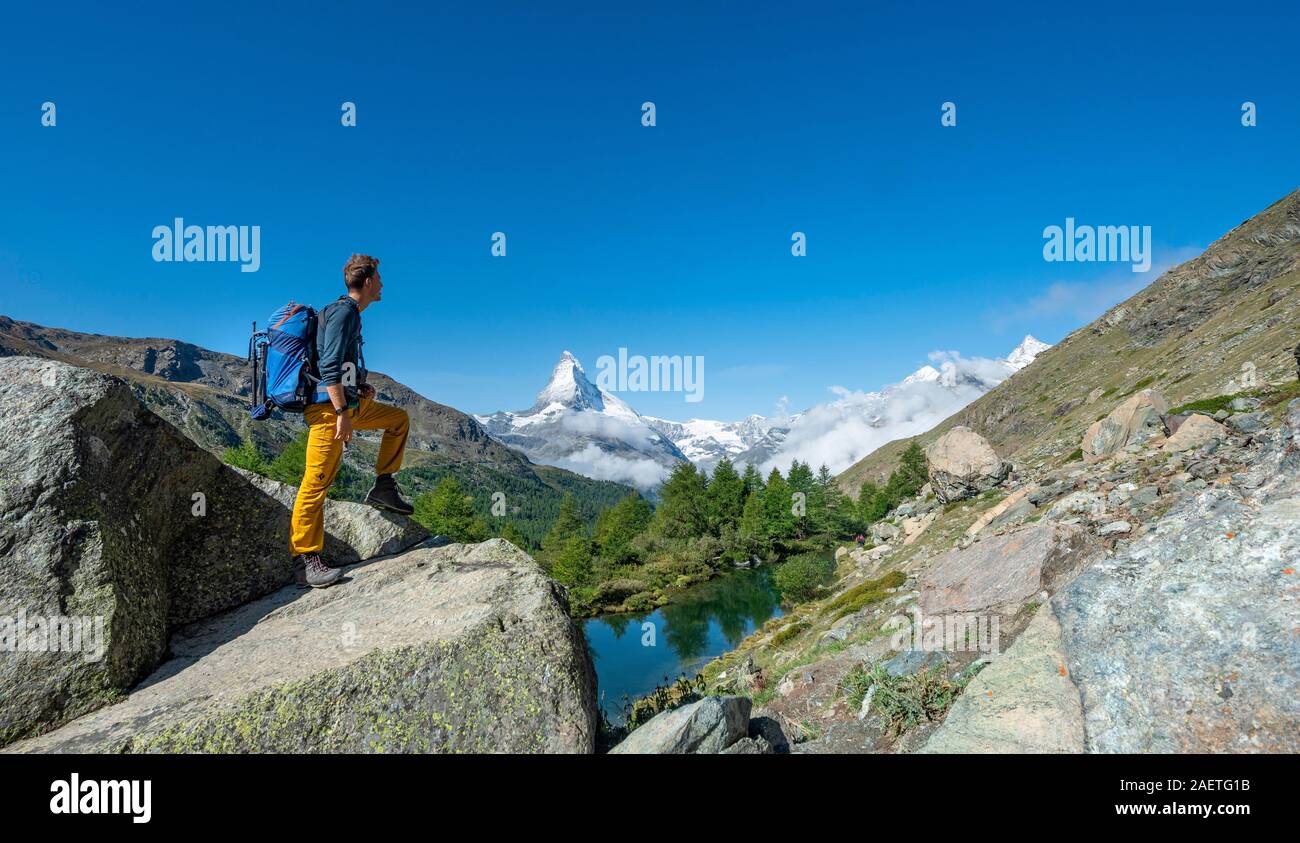 Randonneur se dresse sur les rochers et se penche sur la distance, derrière le Lac de Grindij couverte de neige et Cervin, Valais, Suisse Banque D'Images