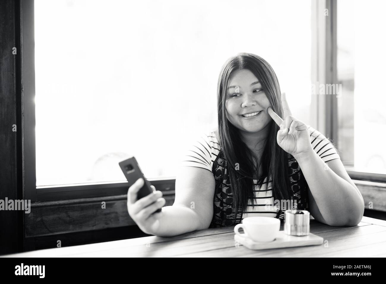 Belle femme asiatique de l'embonpoint se détendre au café Banque D'Images