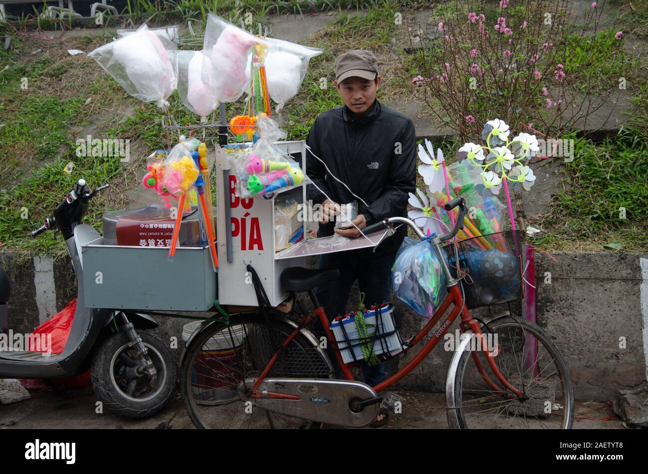 Un homme vend bò bía (doux), popiah Cotton Candy, et des jouets de sa route vélo à Hanoi, Vietnam Banque D'Images