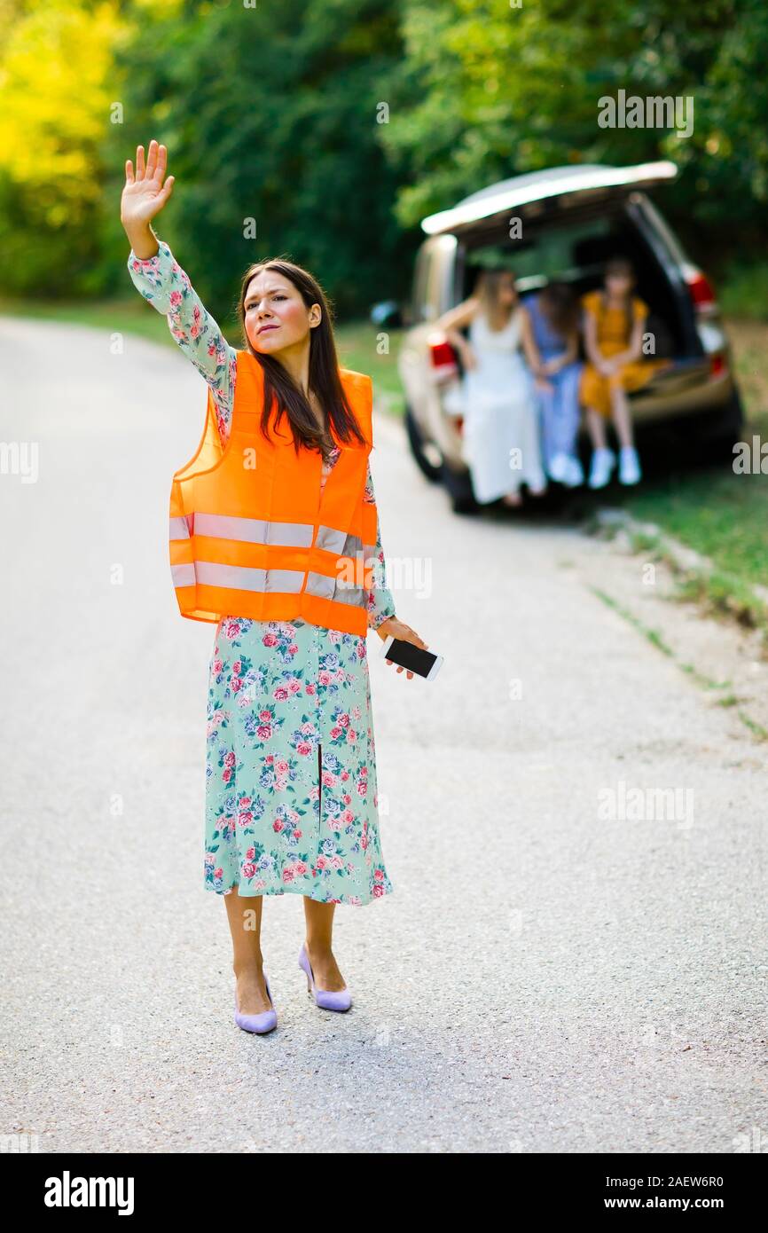 Femme en orange gilet réfléchissant est contagieux car ayant cassé, voiture en famille retour Banque D'Images