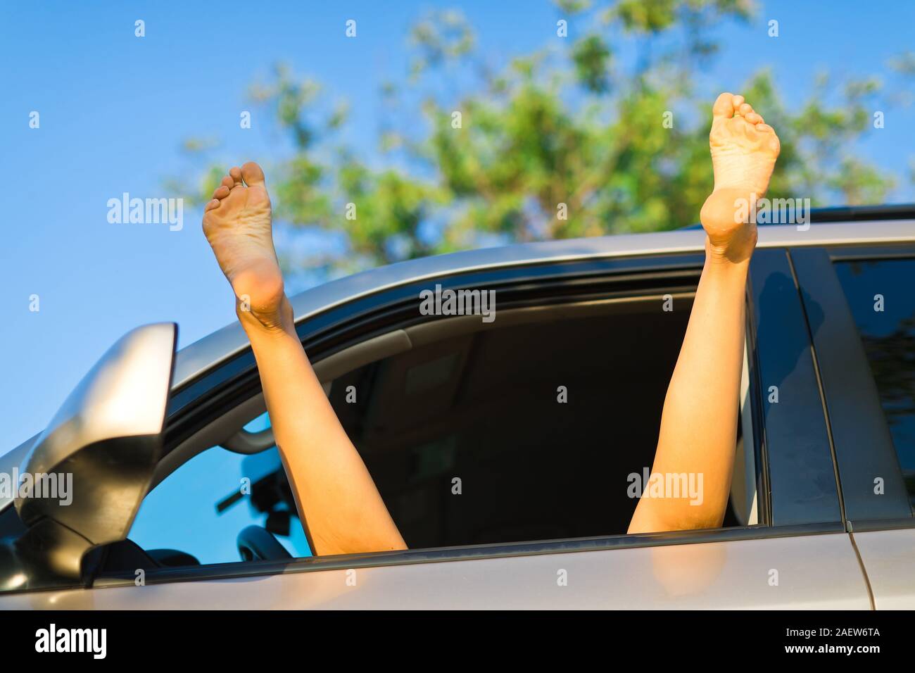 Prostituée à étendre les jambes exposées hors de fenêtre de voiture, pieds nus Banque D'Images