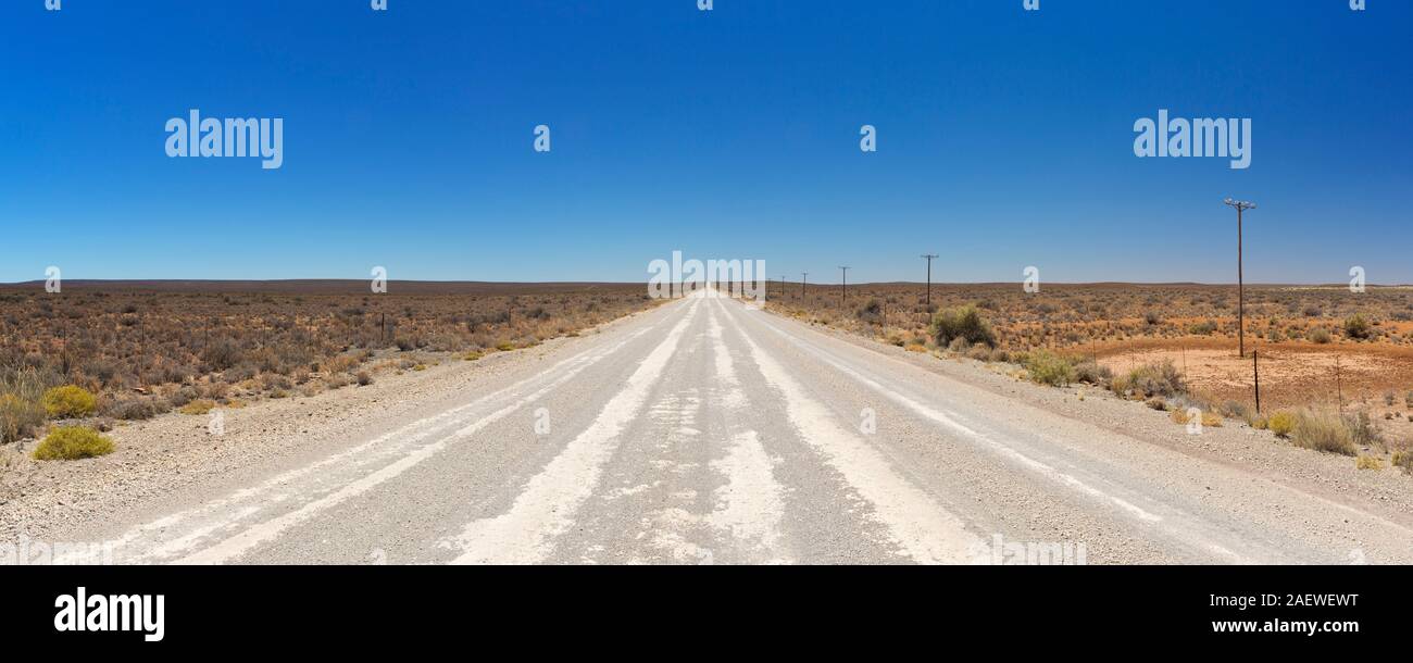 Un chemin de terre tout droit à travers la semi-désertique du Karoo sec en Afrique du Sud. Banque D'Images