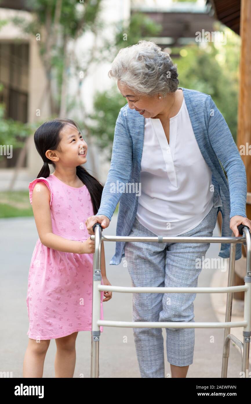 Senior woman walking with walking châssis sous l'assistance de petite-fille Banque D'Images