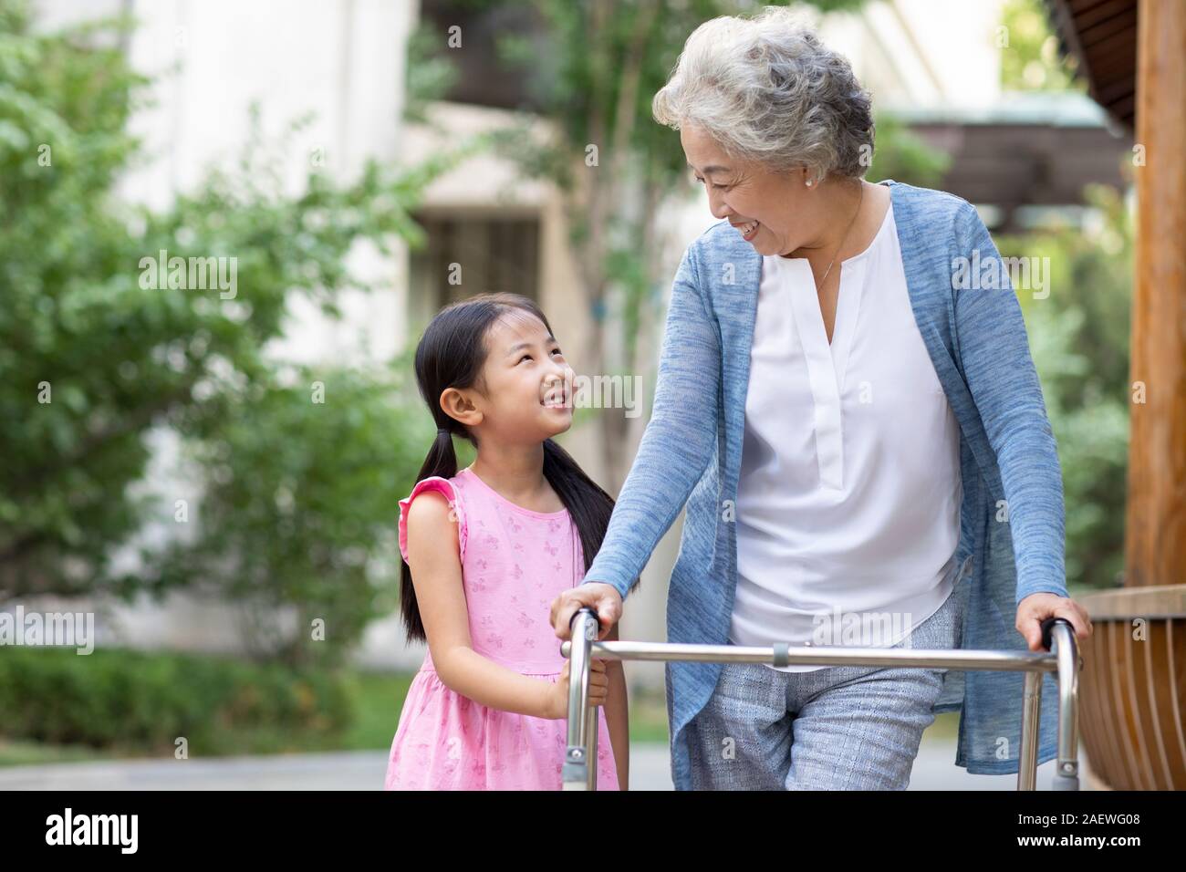 Senior woman walking with walking châssis sous l'assistance de petite-fille Banque D'Images