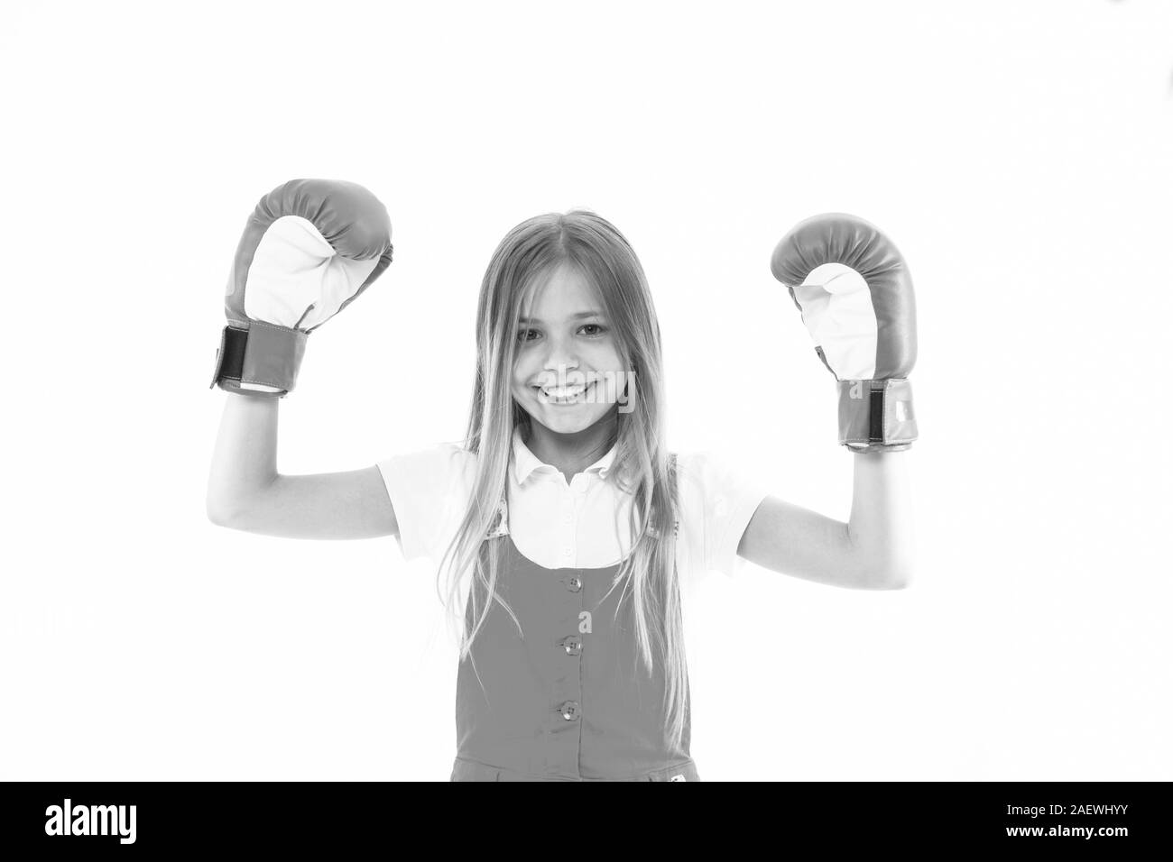 L'enfance et de l'enfants. Kid show power de l'athlète. Heureux l'enfant dans des gants de boxe isolé sur blanc. Sourire petite fille avant l'entraînement ou d'entraînement. L'activité sportive et de l'énergie. Banque D'Images