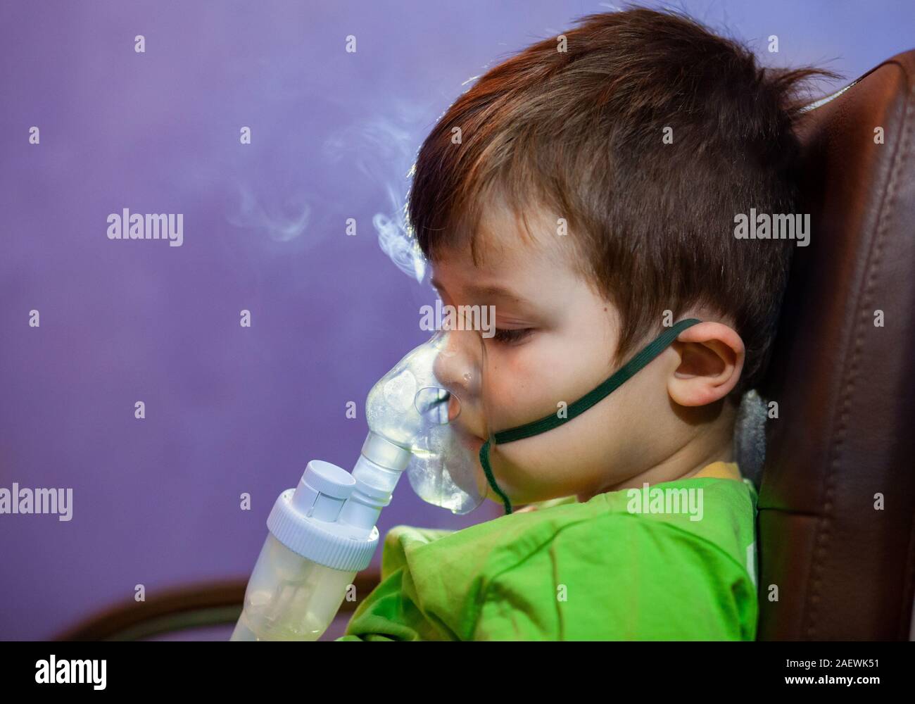 Petit garçon dans un masque, les traitements des voies respiratoires avec  un pulvérisateur à la maison. Siège bébé avec un nébulisateur dans sa  bouche, inhalateur, le traitement de la bronchite Photo Stock 