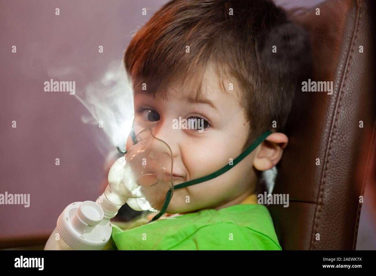 Petit garçon dans un masque, les traitements des voies respiratoires avec  un pulvérisateur à la maison. Siège bébé avec un nébulisateur dans sa  bouche, inhalateur, le traitement de la bronchite Photo Stock 