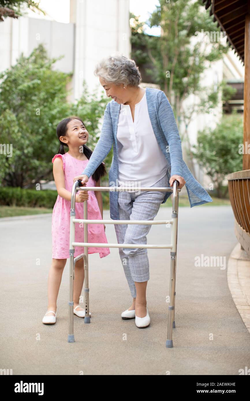 Senior woman walking with walking châssis sous l'assistance de petite-fille Banque D'Images