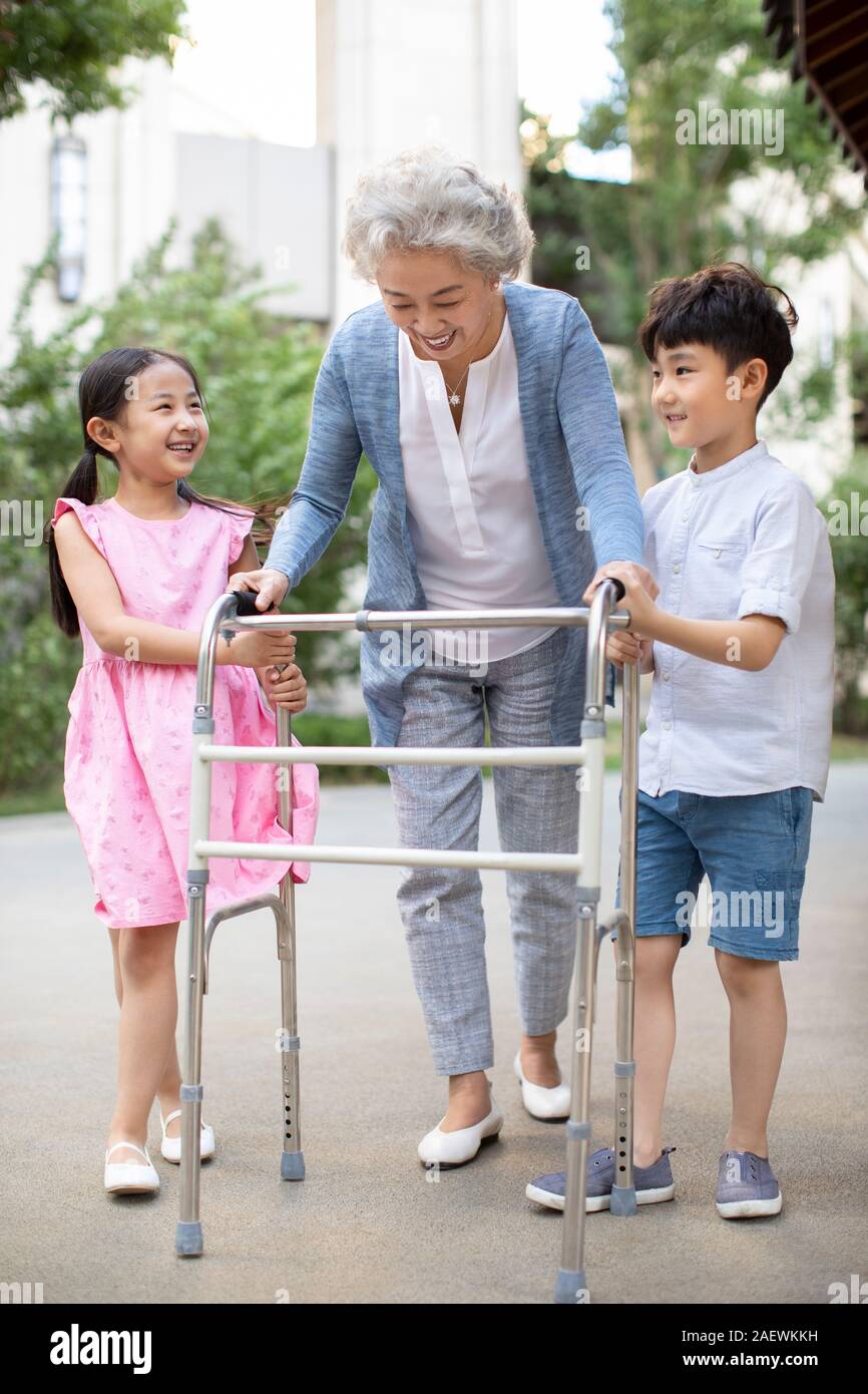 Sœur heureuse d'aider grand-mère marche avec déambulateur Banque D'Images