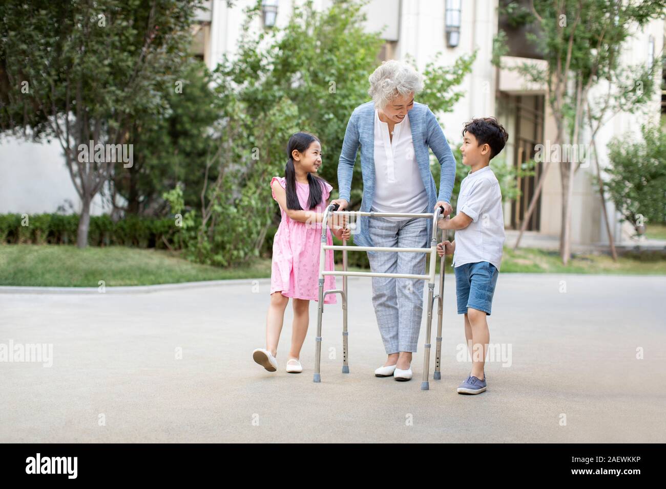Sœur heureuse d'aider grand-mère marche avec déambulateur Banque D'Images