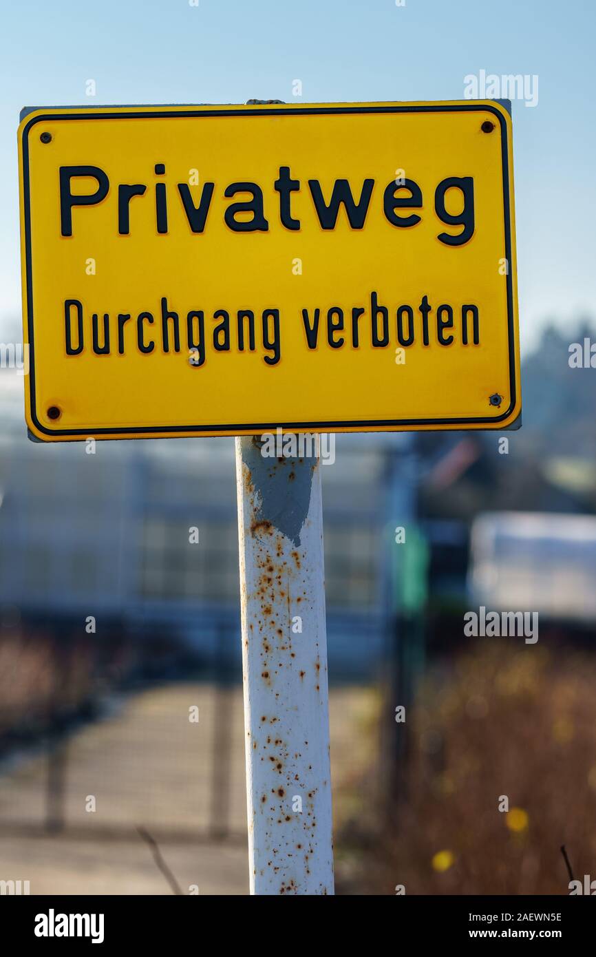 Panneau jaune avec texte allemand 'chemin privé entrée interdite' sur une journée ensoleillée. Out-of-focus chambre avec clôture dans le contexte - gros plan, format vertical Banque D'Images