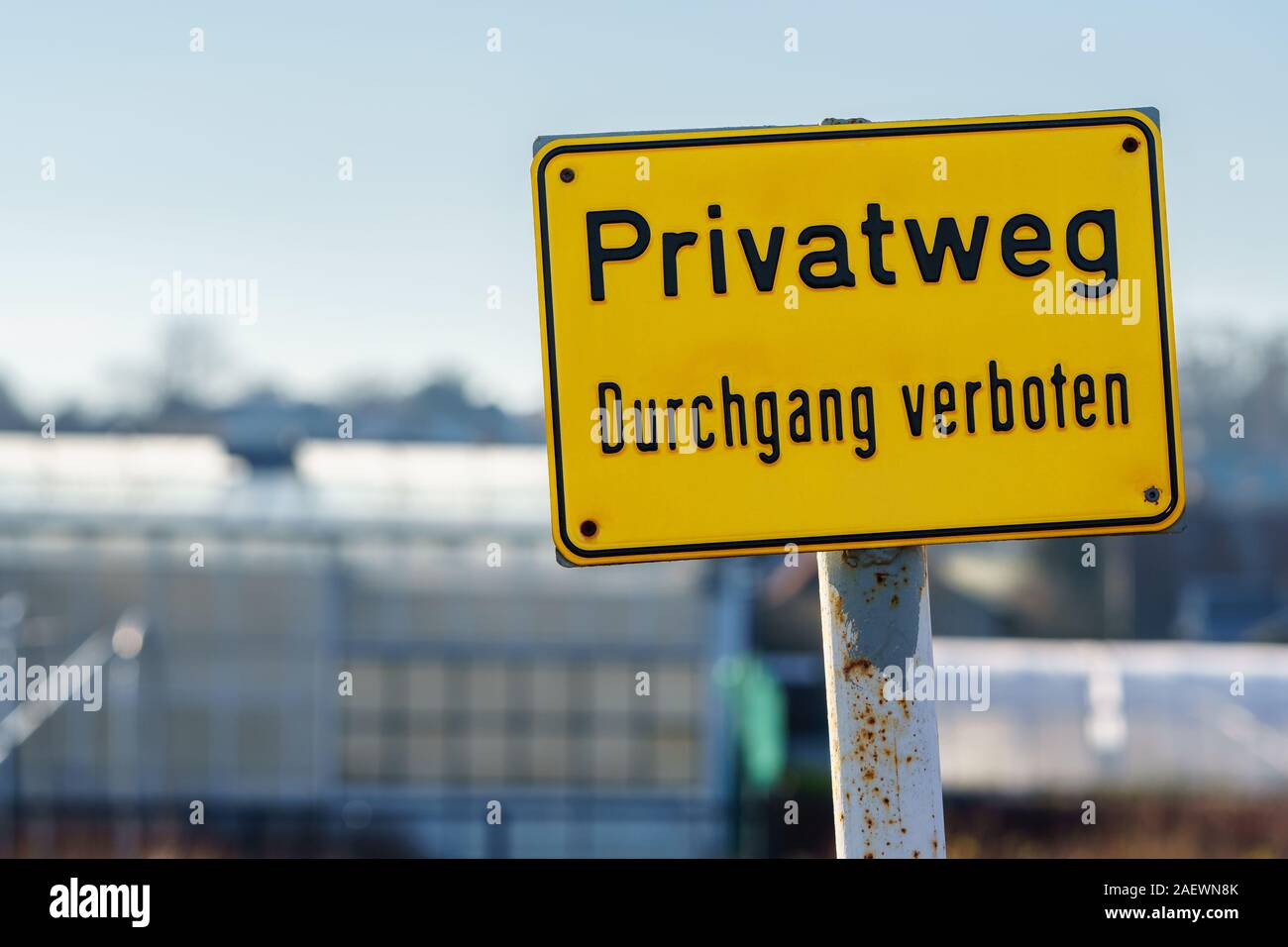 Panneau jaune avec texte allemand 'chemin privé entrée interdite' sur une journée ensoleillée. Out-of-focus comme arrière-plan de construction - gros plan, format paysage Banque D'Images