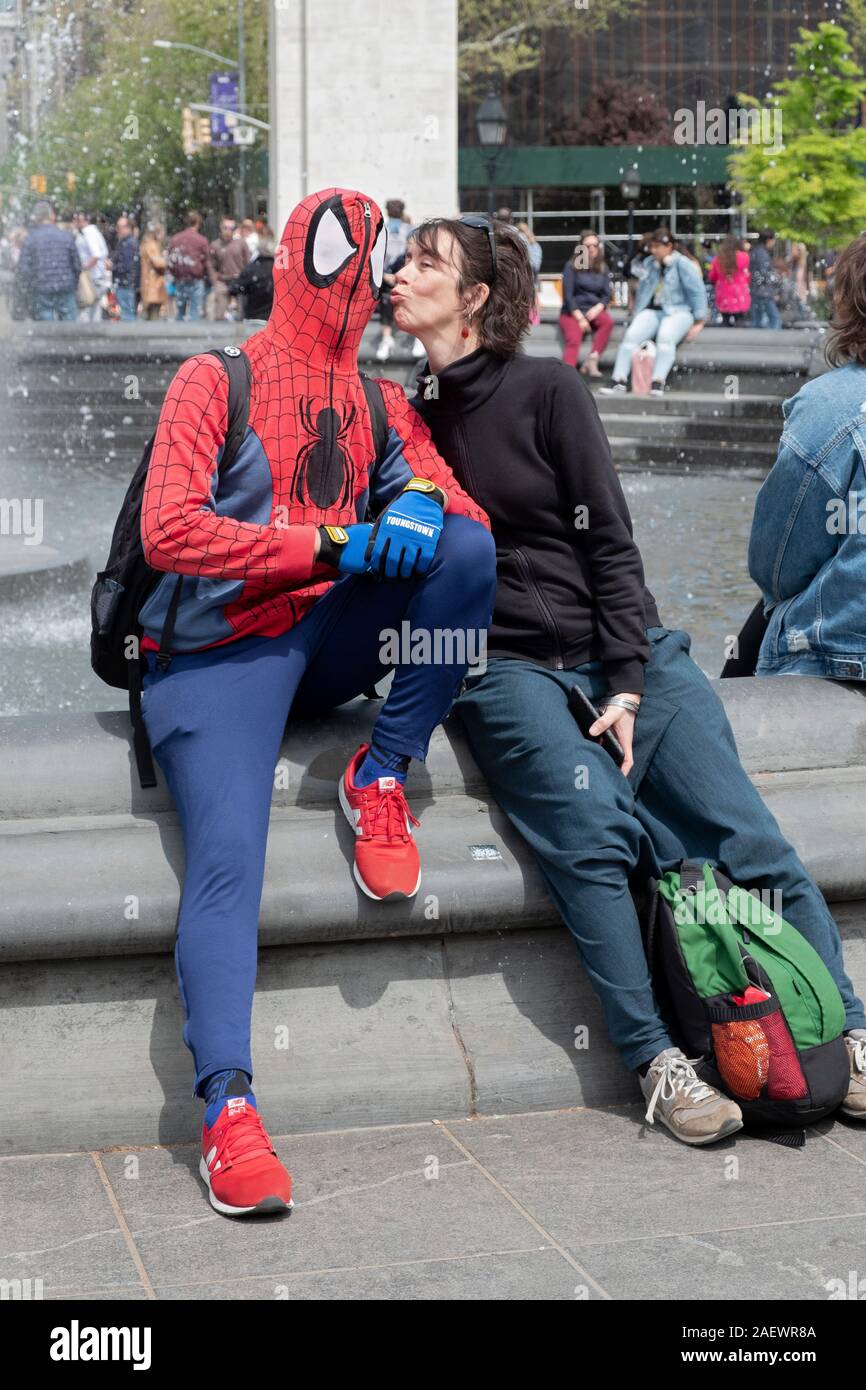 Un drôle de photo d'un touriste italien Spiderman embrassant un musicien ambulant à Washington Square Park à Greenwich Village, Manhattan, New York. Banque D'Images