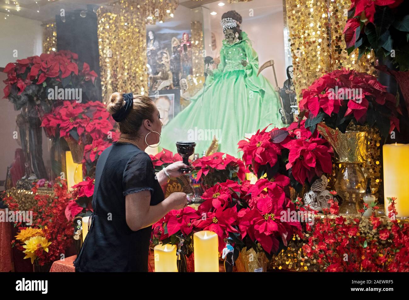A Santa Muerte prêtresse dirige un service dans sa maison temple à Jackson Heights, Queens, New York. Elle souffle la fumée à une divinité comme c'est une coutume. Banque D'Images