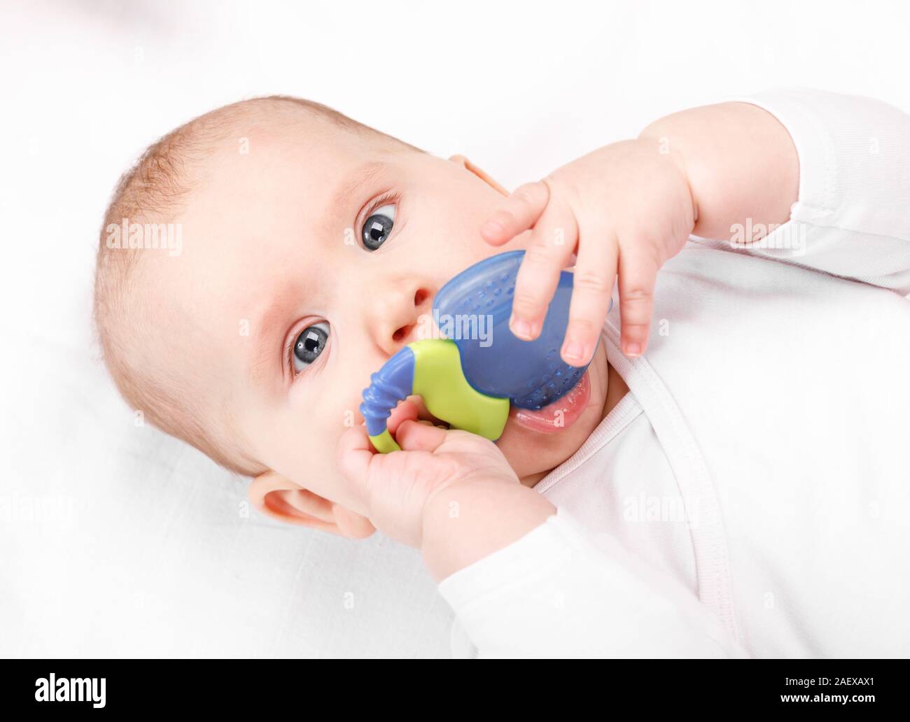 Six Mois Bebe Fille Macher Jouet De Dentition En Plastique Couche Sur Son Dos Looking At Camera Photo Stock Alamy