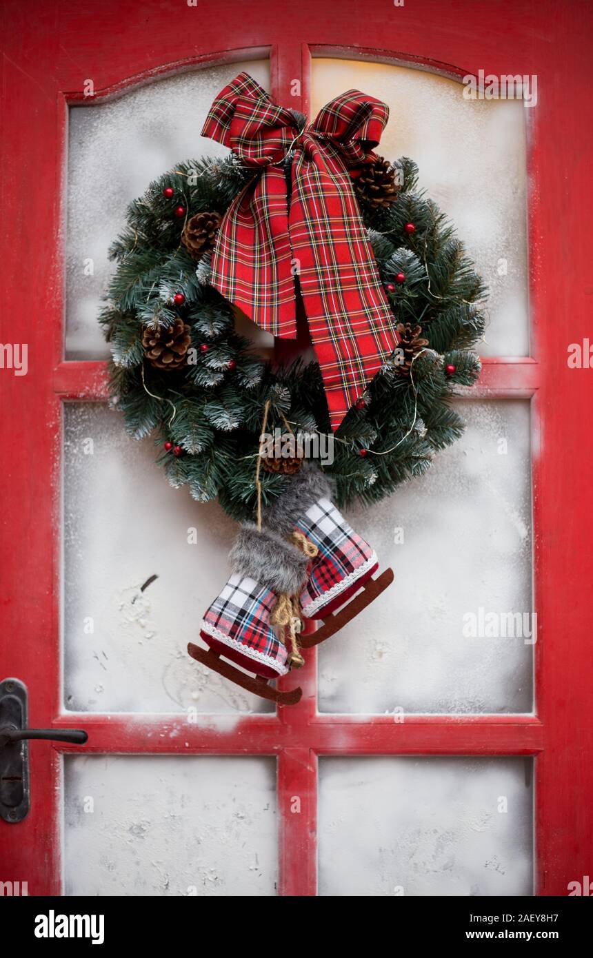 Evergreen Noël couronne fait main avec les cônes et ruban sur une porte rouge. Banque D'Images