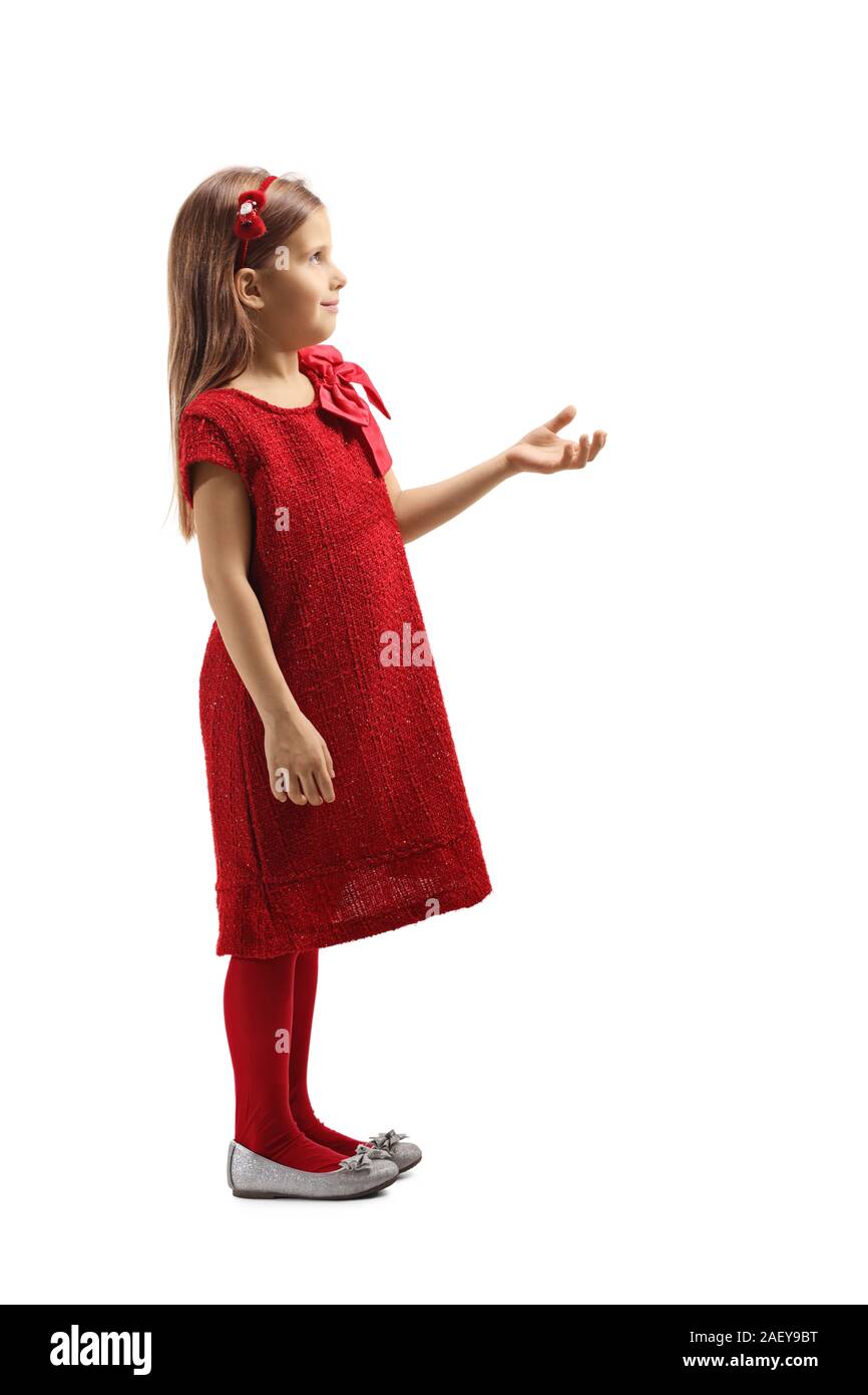 Profil tourné sur toute la longueur d'une petite fille dans une robe rouge tenant sa main et l'attente avant isolé sur fond blanc Banque D'Images