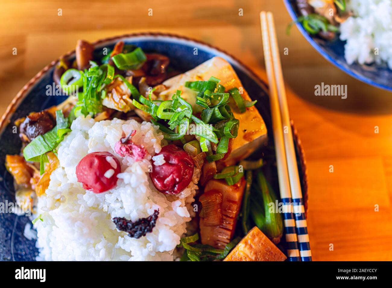 La plaque traditionnelle japonaise télévision haut Vue sur table en bois aux légumes avec du riz blanc, baguettes, umeboshi shiso et pousses de bambou avec vert o Banque D'Images