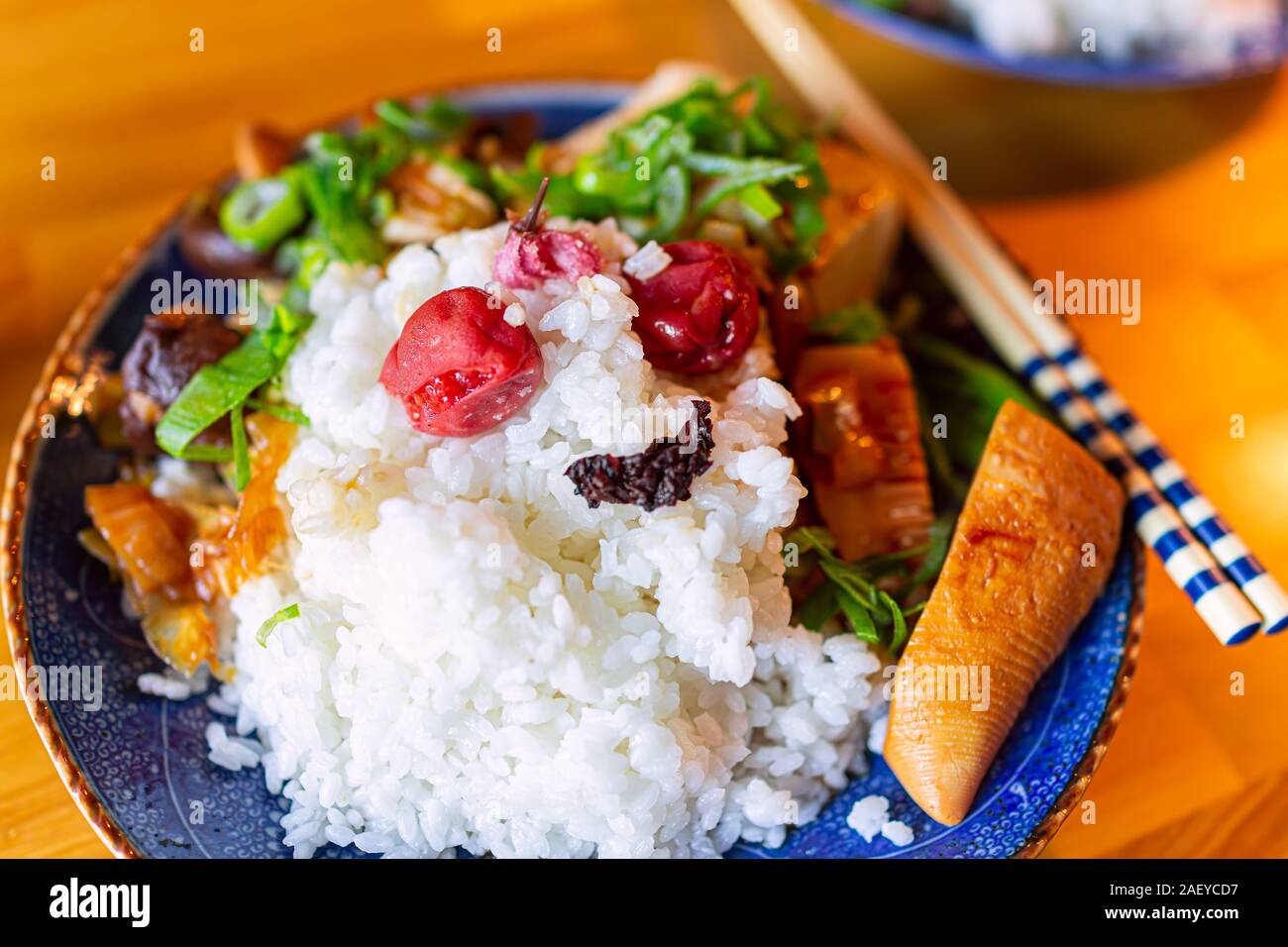 La plaque traditionnelle japonaise sur table en bois aux légumes avec du riz blanc, baguettes, umeboshi shiso et pousses de bambou d'oignons verts Banque D'Images
