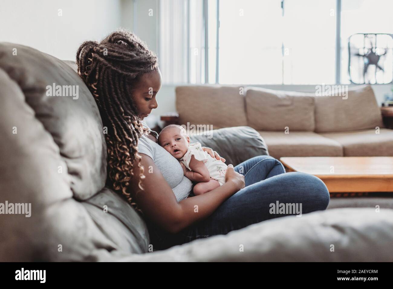 Mère ethnique avec de longues tresses holding newborn multiraciale Banque D'Images