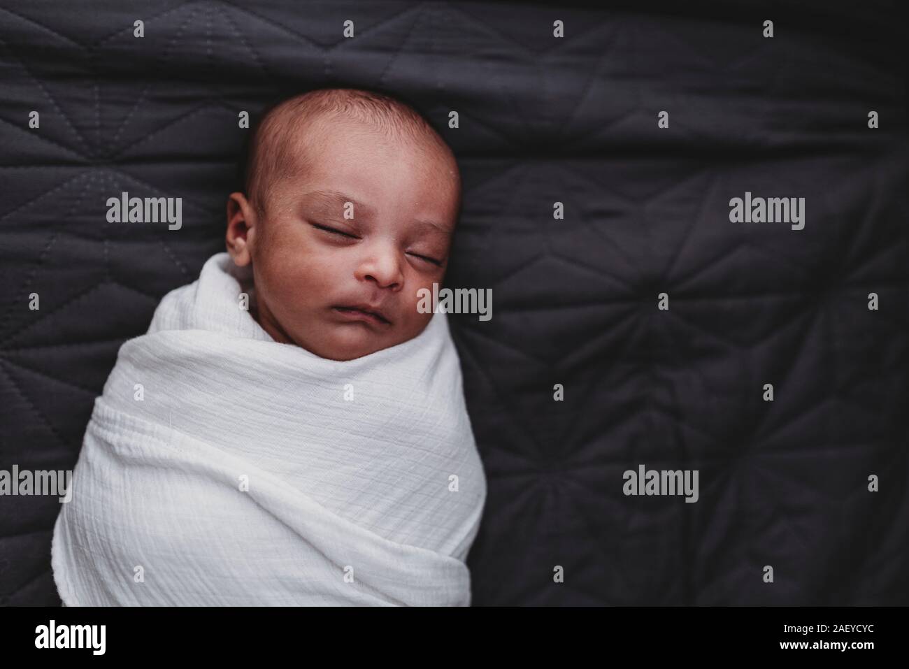 Dormir enveloppé dans du nouveau-né multiraciale couverture blanche Banque D'Images