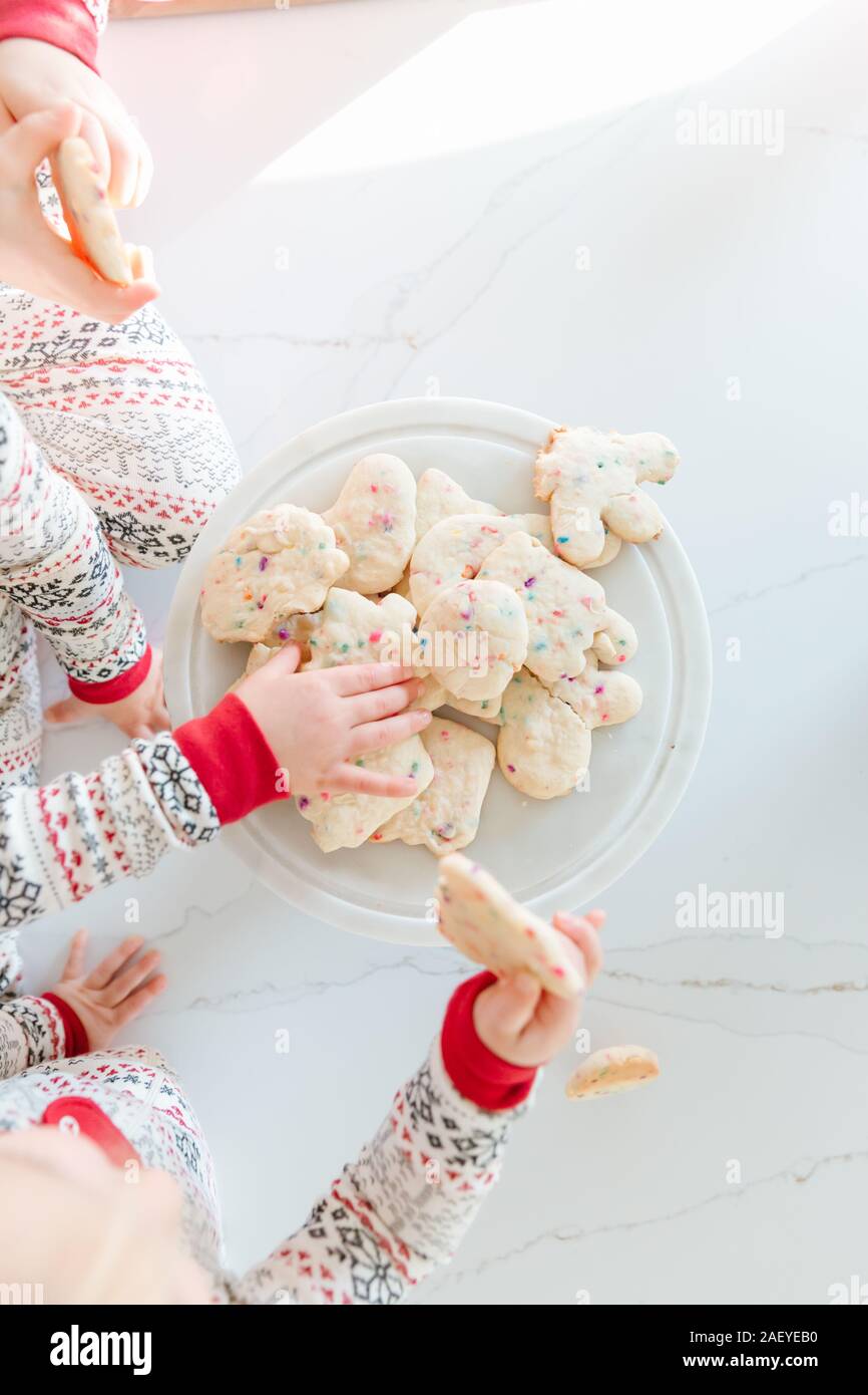 Les tout-petits mains tendues pour les biscuits de Noël en pyjama. Banque D'Images