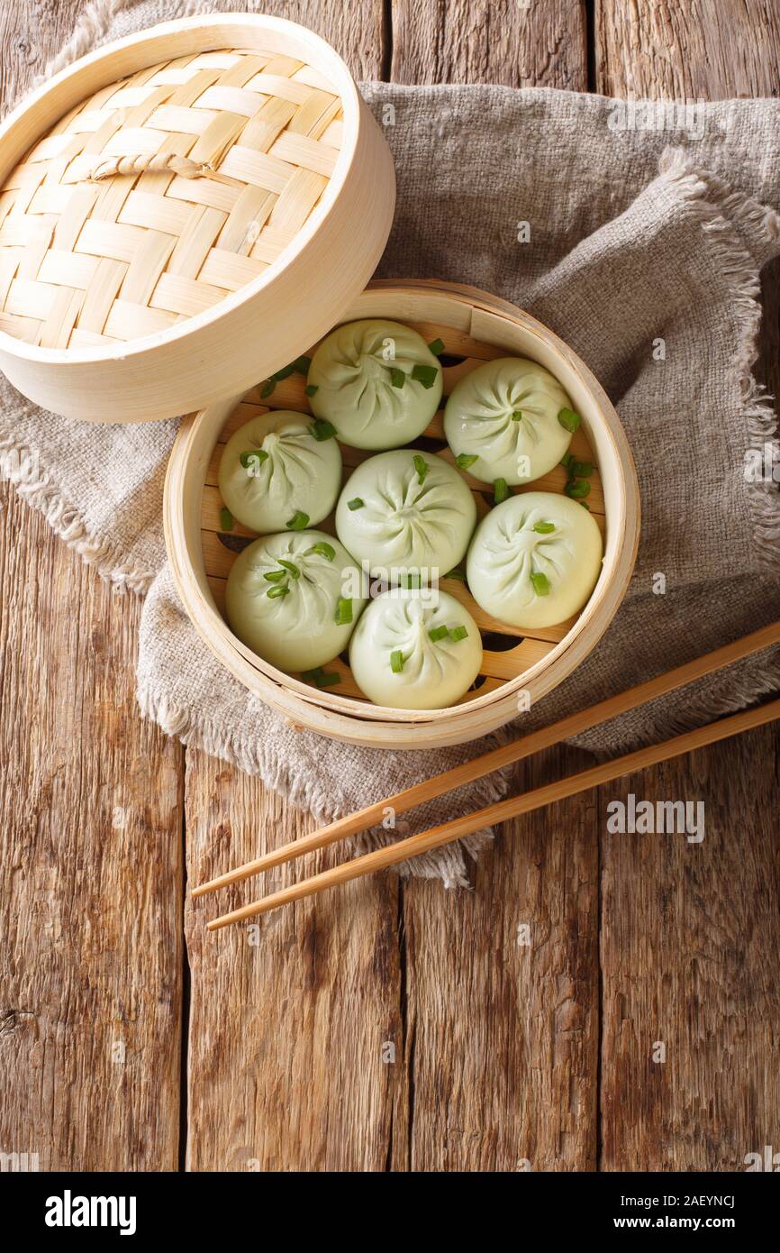 Brioches à la vapeur baozi en bateau à vapeur de bambou chinois gros plan sur la table. Haut Vertical Vue de dessus Banque D'Images