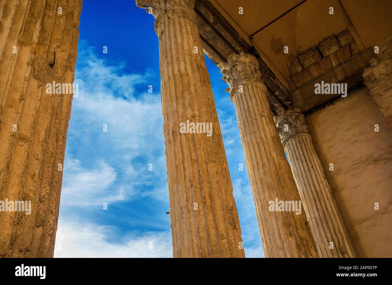 L'architecture romaine antique et d'archéologie à Assise. Temple de Minerve anciennes colonnes avec teinte dorée au coucher du soleil et nuages (1er siècle avant J.-C.) Banque D'Images