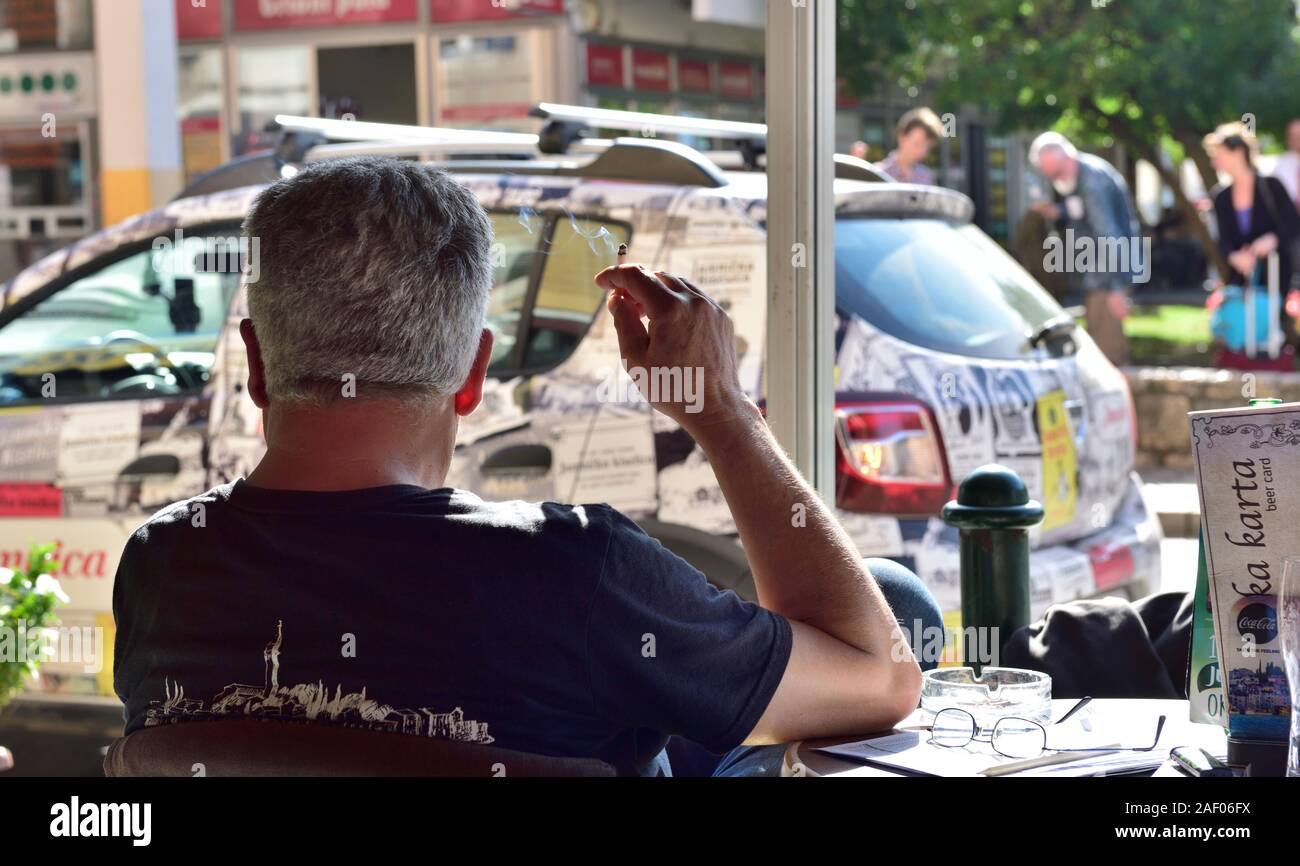 L'homme assis à l'intérieur table cafe cigarette avec cendrier sur tableau Rovinj, Istrie, Croatie Banque D'Images