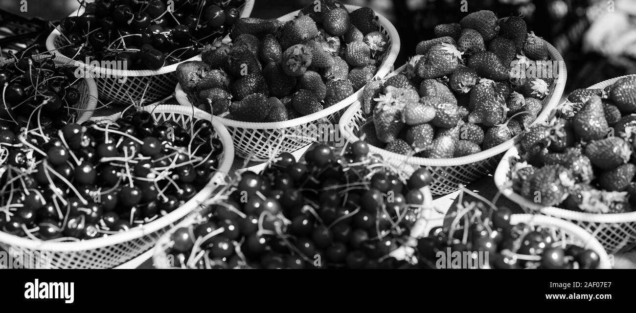 Des baies. Les cerises et les fraises dans des paniers pour les vendre. Marché à la ferme. La récolte d'été. Les baies mûres rouges. Petits fruits juteux de jardin. Acheter des fruits frais. Petits fruits biologiques. Des en-cas délicieux. Banque D'Images