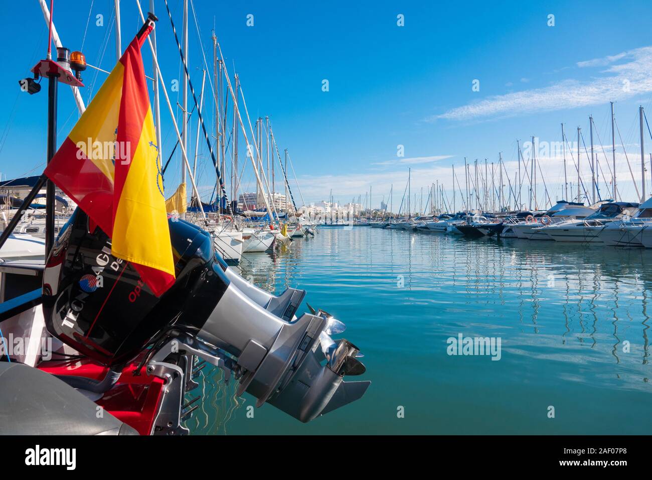 Grande chambre lits jumeaux, moteurs hors-bord, soulevée à l'arrière d'un bateau dans l'avant-plan d'une marina à Santa Pola, Espagne. Banque D'Images